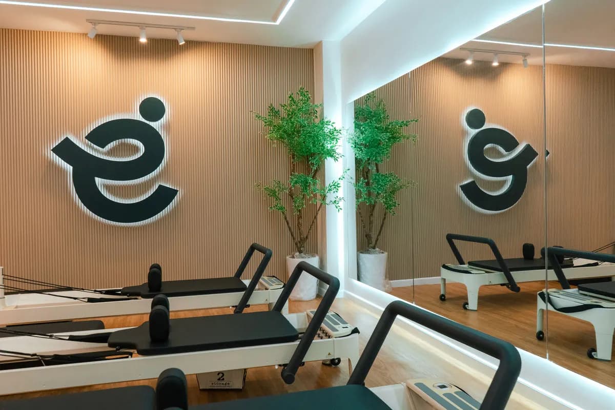 The lit e.space logo on a wood-slat wall, with reformers in front, a mirror and plants